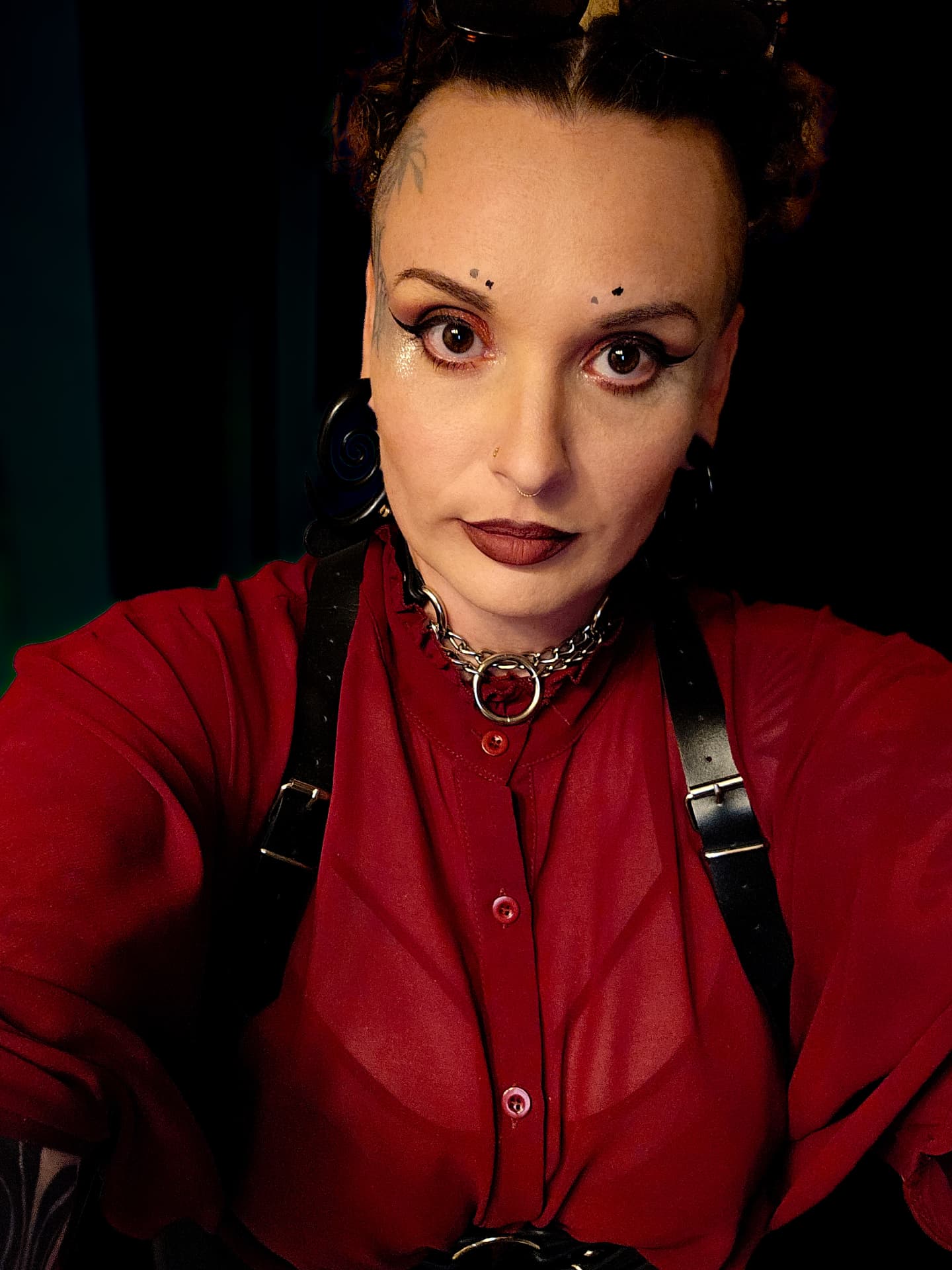 Kara Kozlowski, tattoo artist, facing the camera against a black background
